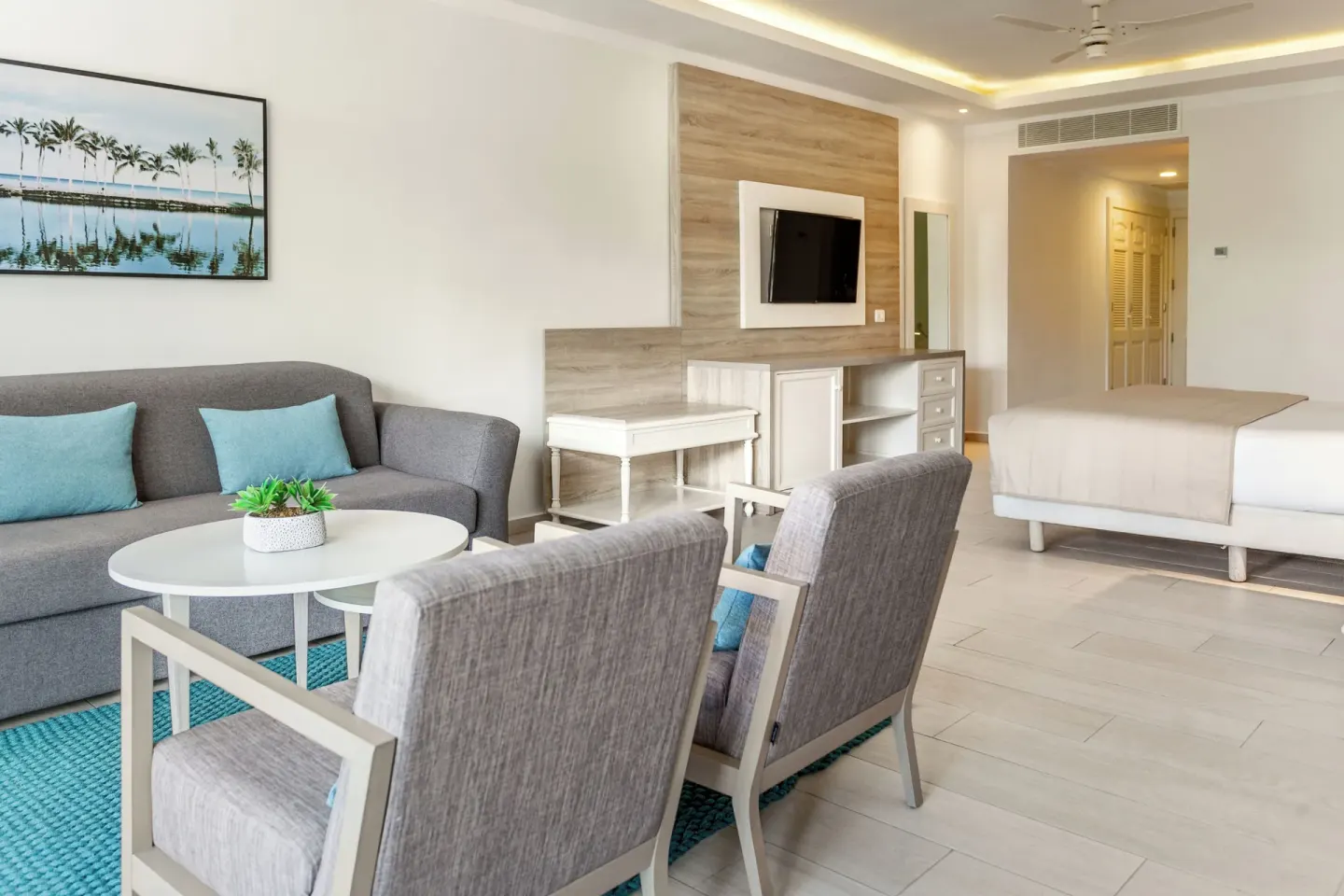 Corner Junior Suite sitting area with sofa and king bed at Bahia Principe Escape Ambar.