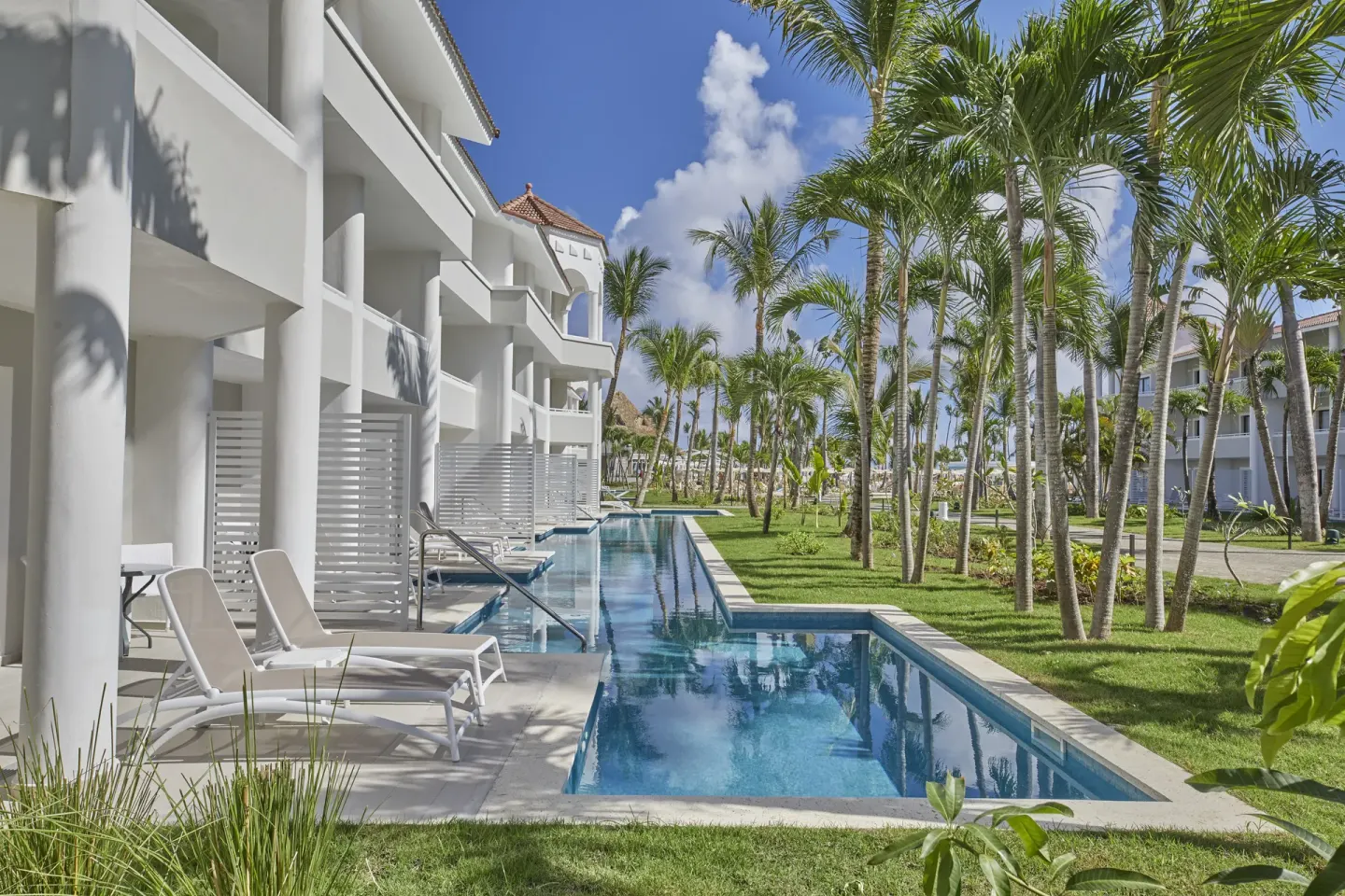 Swim-up suite patios and pool channel through palm gardens at Bahia Principe Escape Ambar.