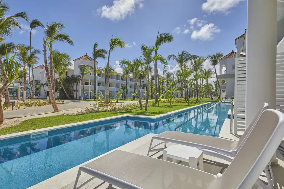 Junior Suite swim-up terrace with loungers beside a long pool at Bahia Principe Escape Ambar.
