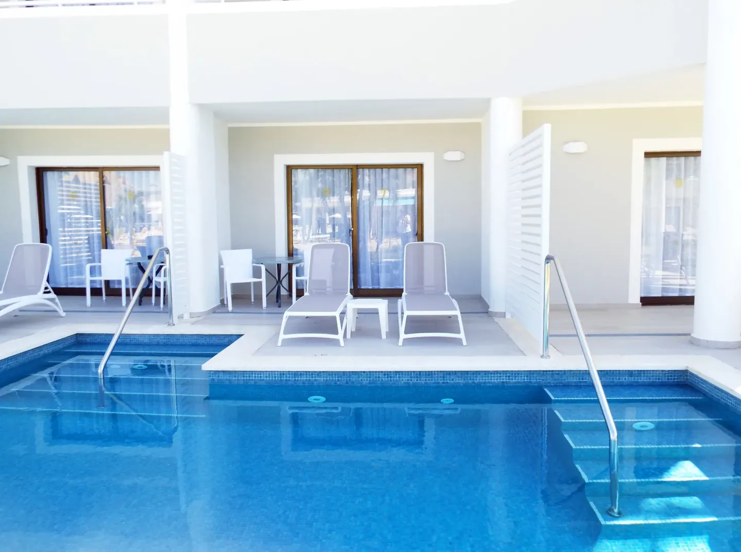 Swim-up Junior Suite terrace with loungers and pool steps at Bahia Principe Escape Ambar.