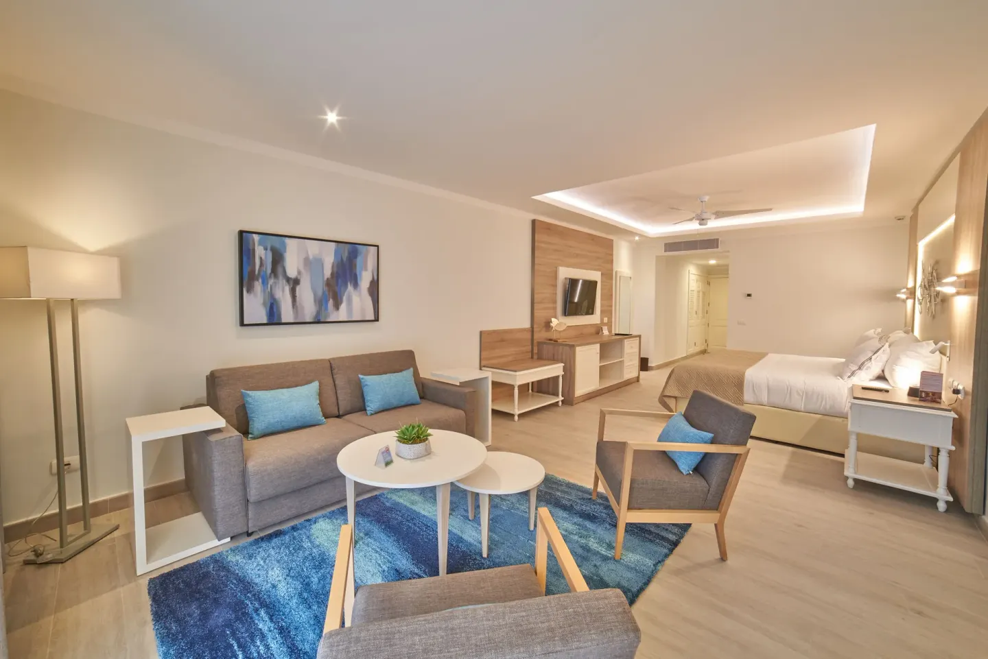 Junior Suite Deluxe with bed, sofa, chairs, and TV at Bahia Principe Escape Ambar.