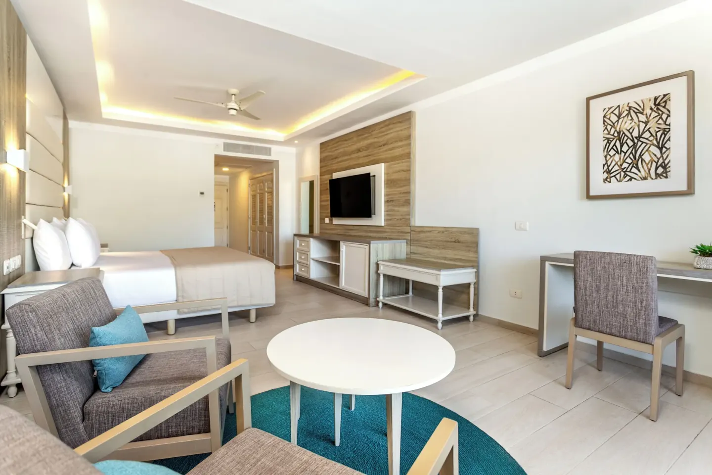Junior Suite deluxe sitting area, desk, and king bed at Bahia Principe Escape Ambar.