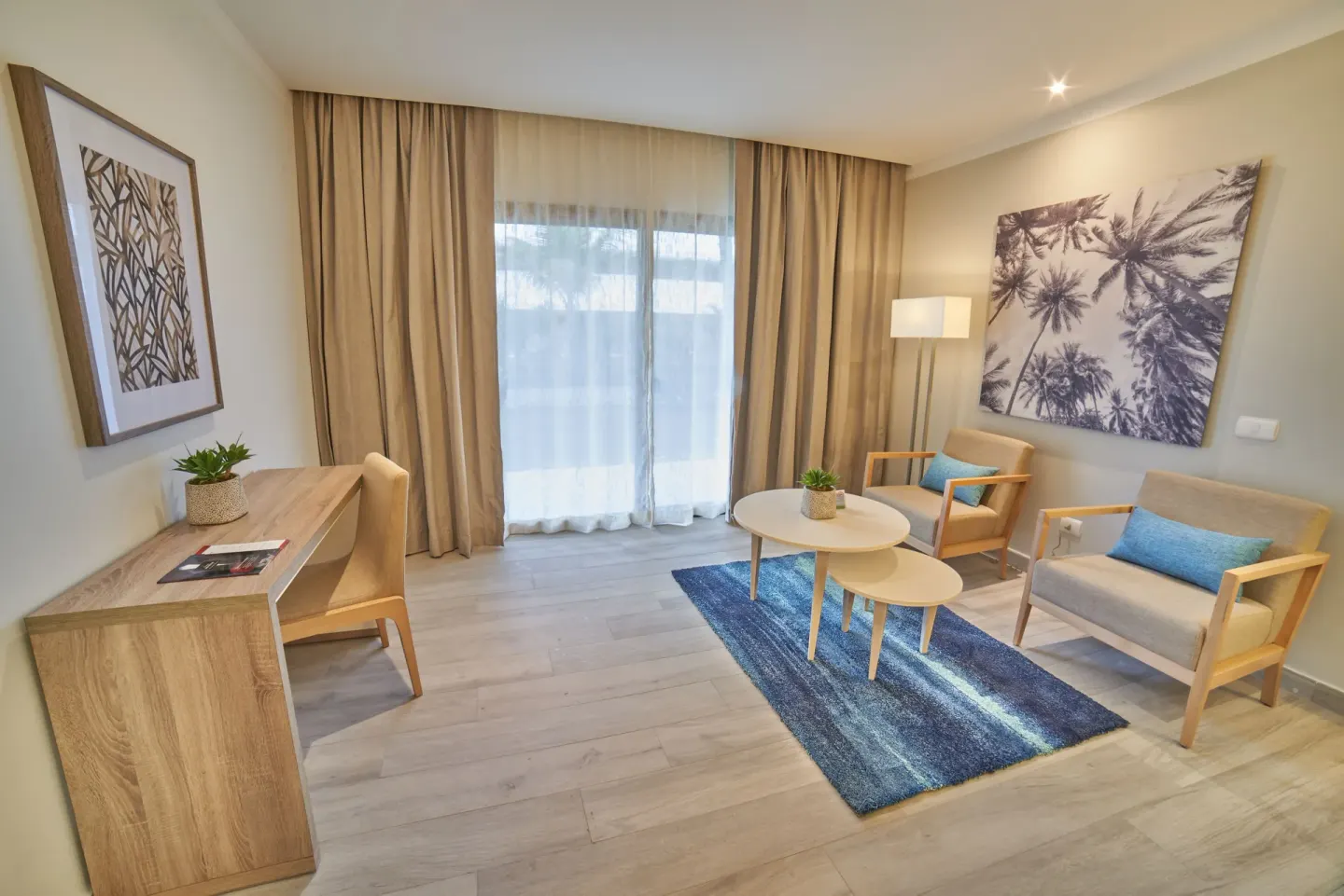 Junior Suite Deluxe lounge with desk and balcony curtains at Bahia Principe Escape Ambar.