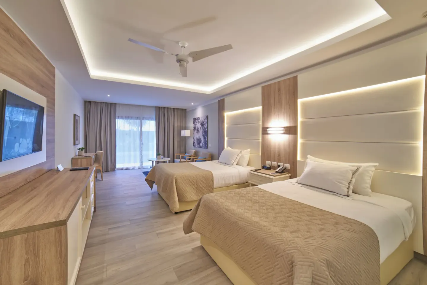 Junior Suite Deluxe with two beds, TV console, and balcony doors at Bahia Principe Escape Ambar.