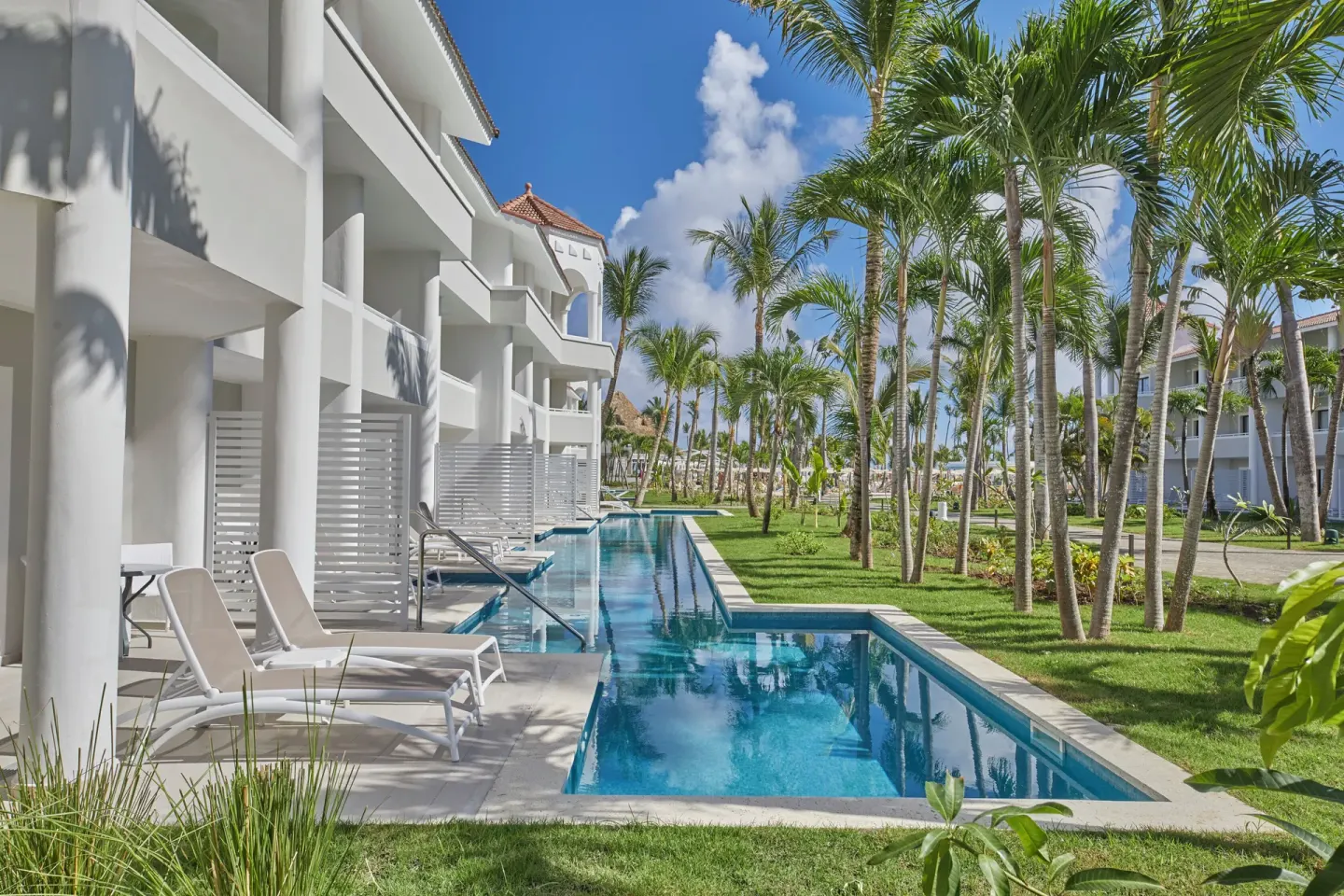 Junior Suite Swim Up building with pool channel and palms at Bahia Principe Escape Ambar.