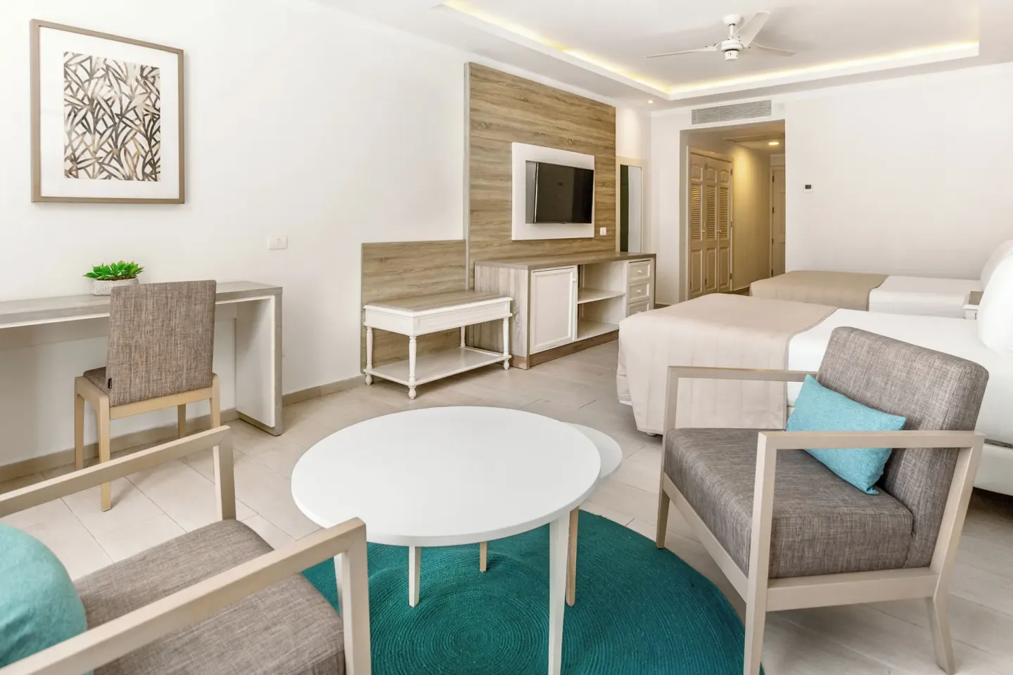 Junior Suite seating area, desk, TV, and two beds at Bahia Principe Escape Ambar.