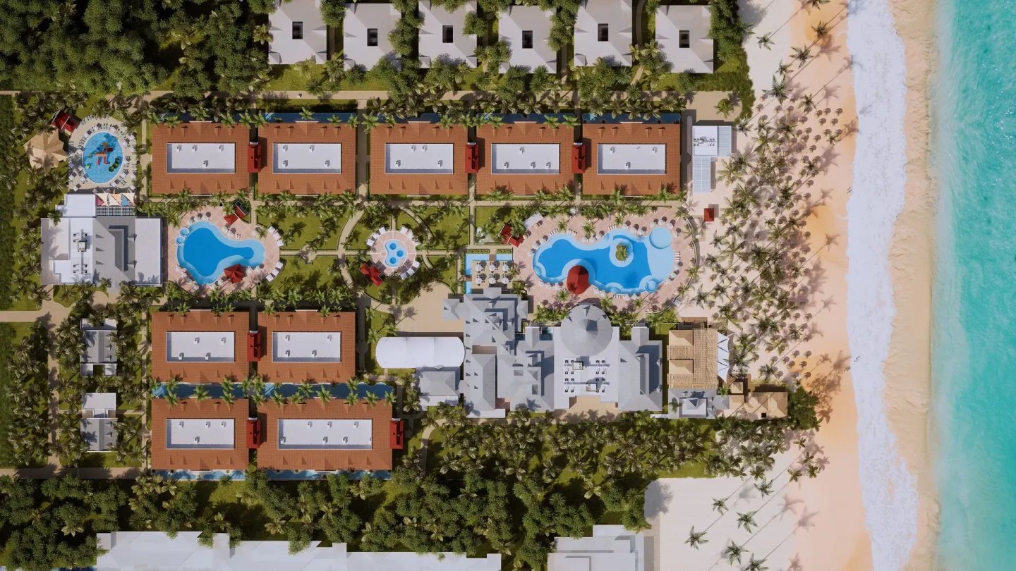 Overhead view of beachfront pools, buildings, palms and sand at Bahia Principe Explore Esmeralda.