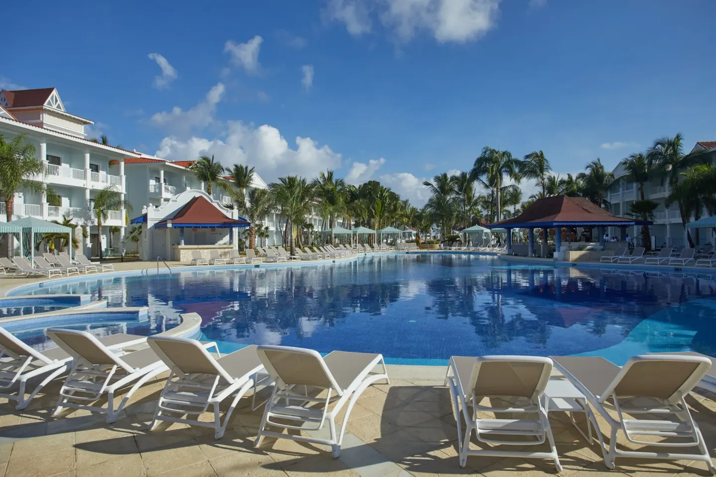 Large daytime pool with loungers and white resort buildings at Bahia Principe Explore Esmeralda.