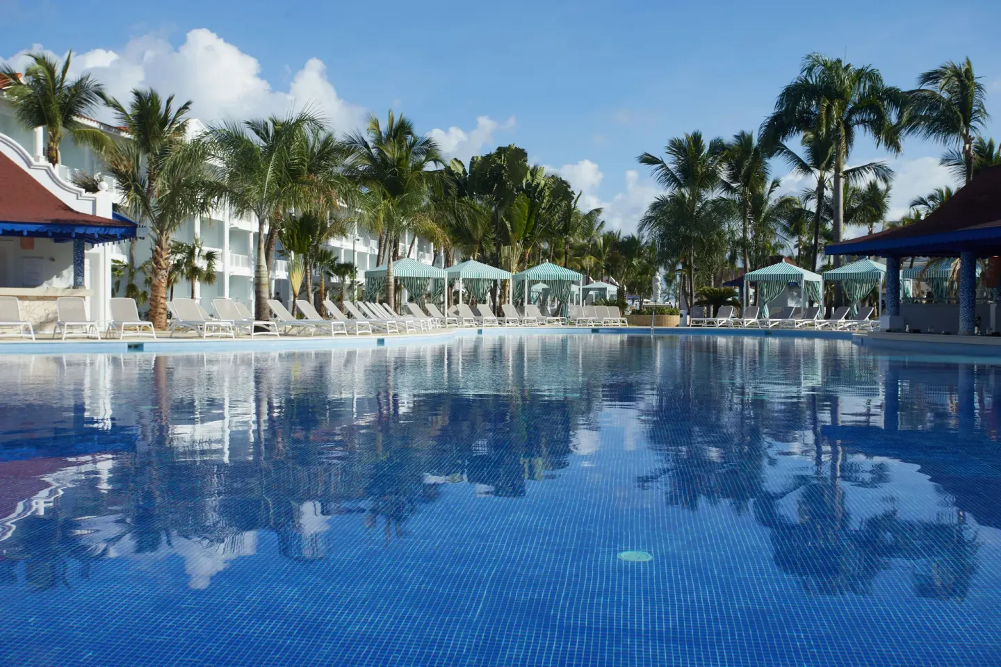 Main pool with loungers, cabanas and palms at Bahia Principe Explore Esmeralda.