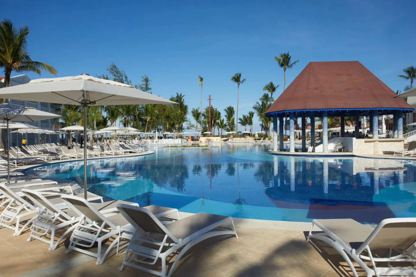 Main pool with loungers, umbrellas and a blue-column pavilion at Bahia Principe Explore Esmeralda.