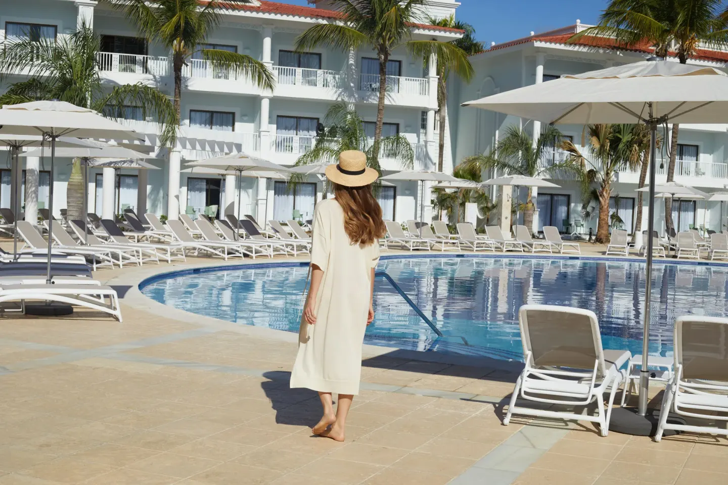 Pool deck with loungers, umbrellas and guest room balconies at Bahia Principe Explore Esmeralda.