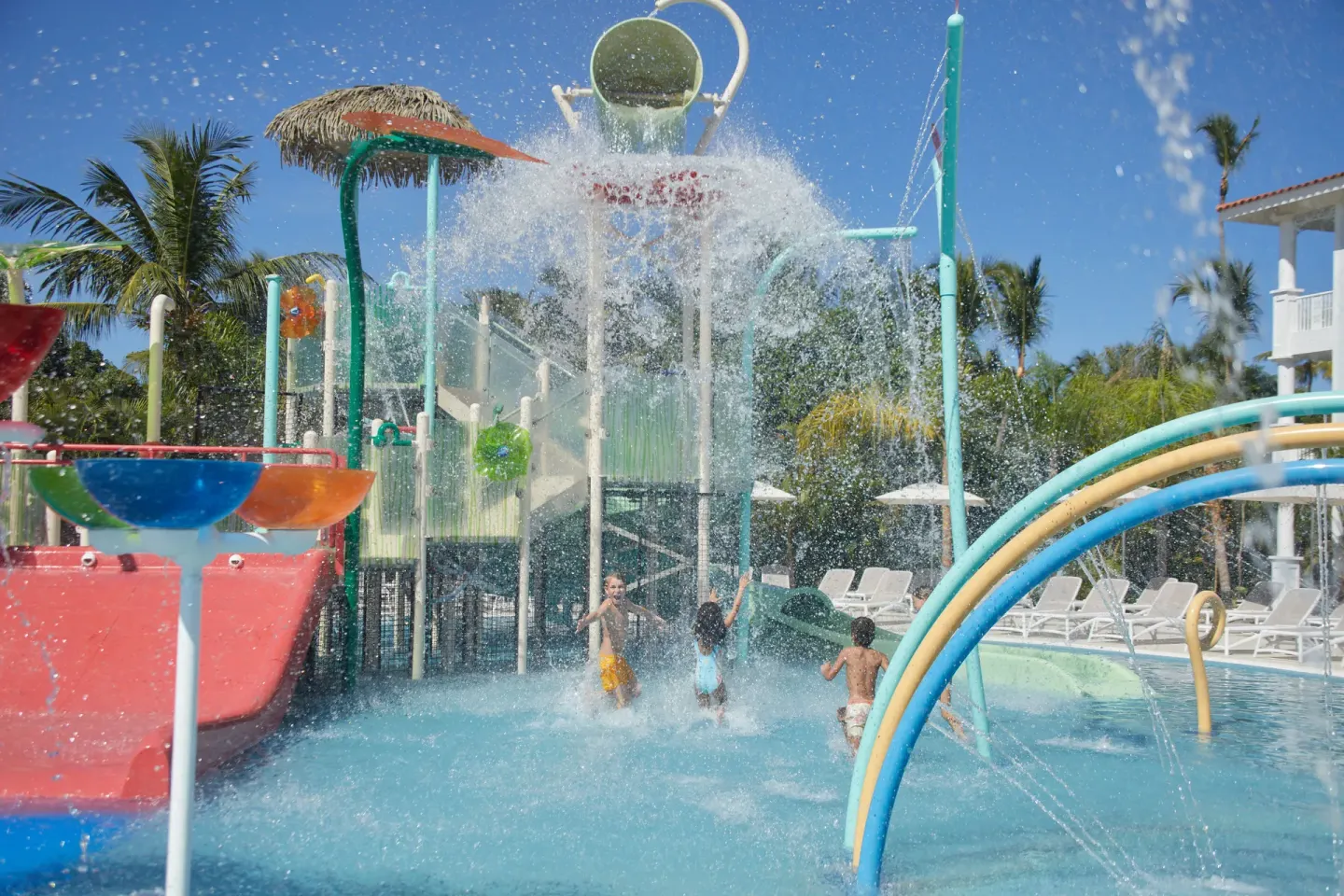 Splash pad bucket pouring water over children at Bahia Principe Explore Esmeralda.