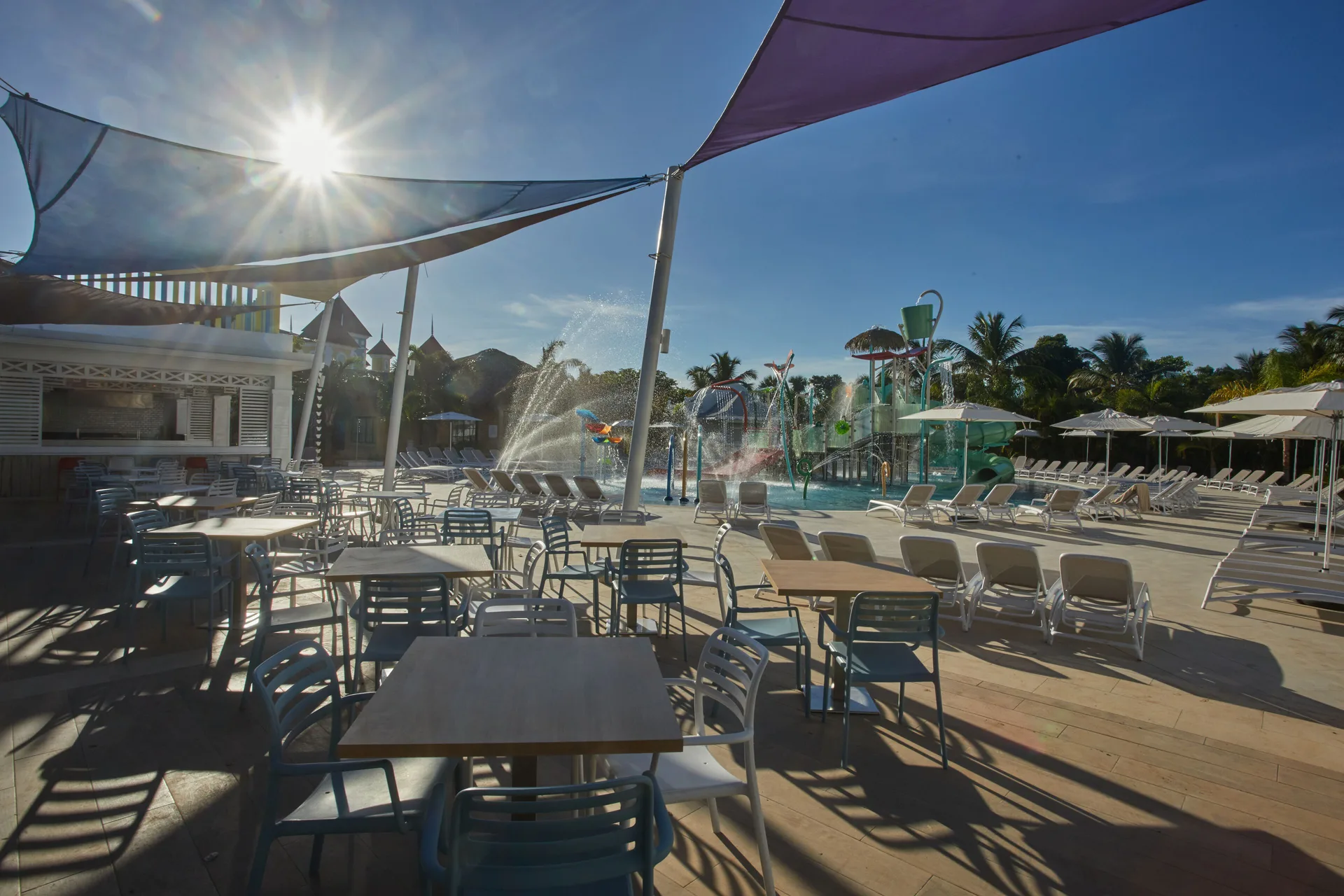 Sunlit splash pool with loungers and shaded tables at Bahia Principe Explore Esmeralda.