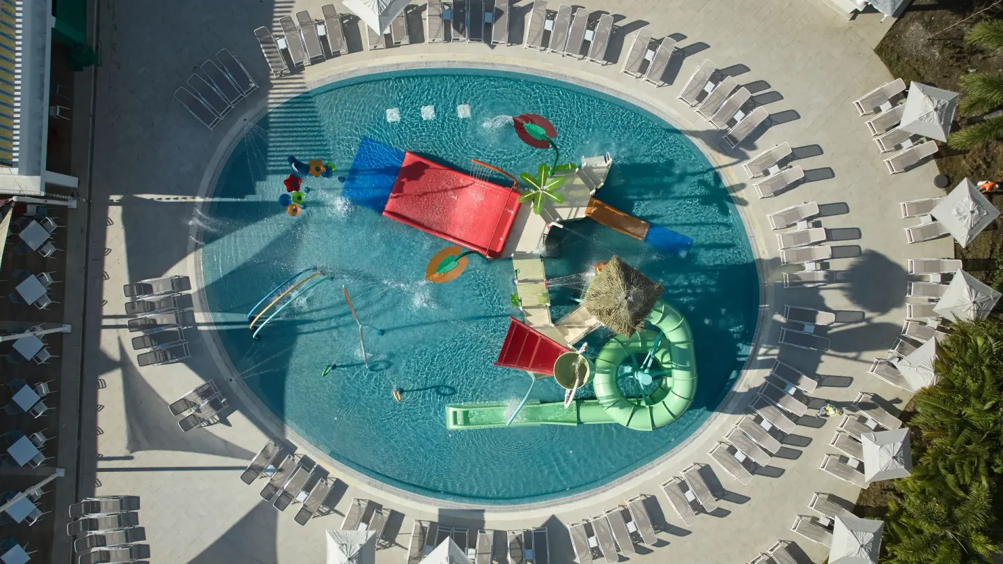 Top-down view of children's pool slides and loungers at Bahia Principe Explore Esmeralda.