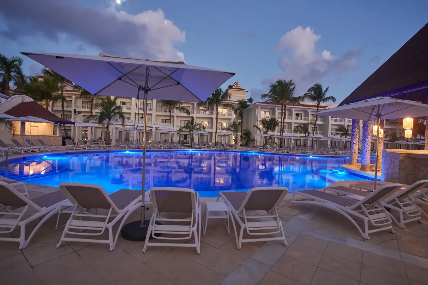 Poolside loungers and umbrellas at twilight at Bahia Principe Explore Esmeralda.