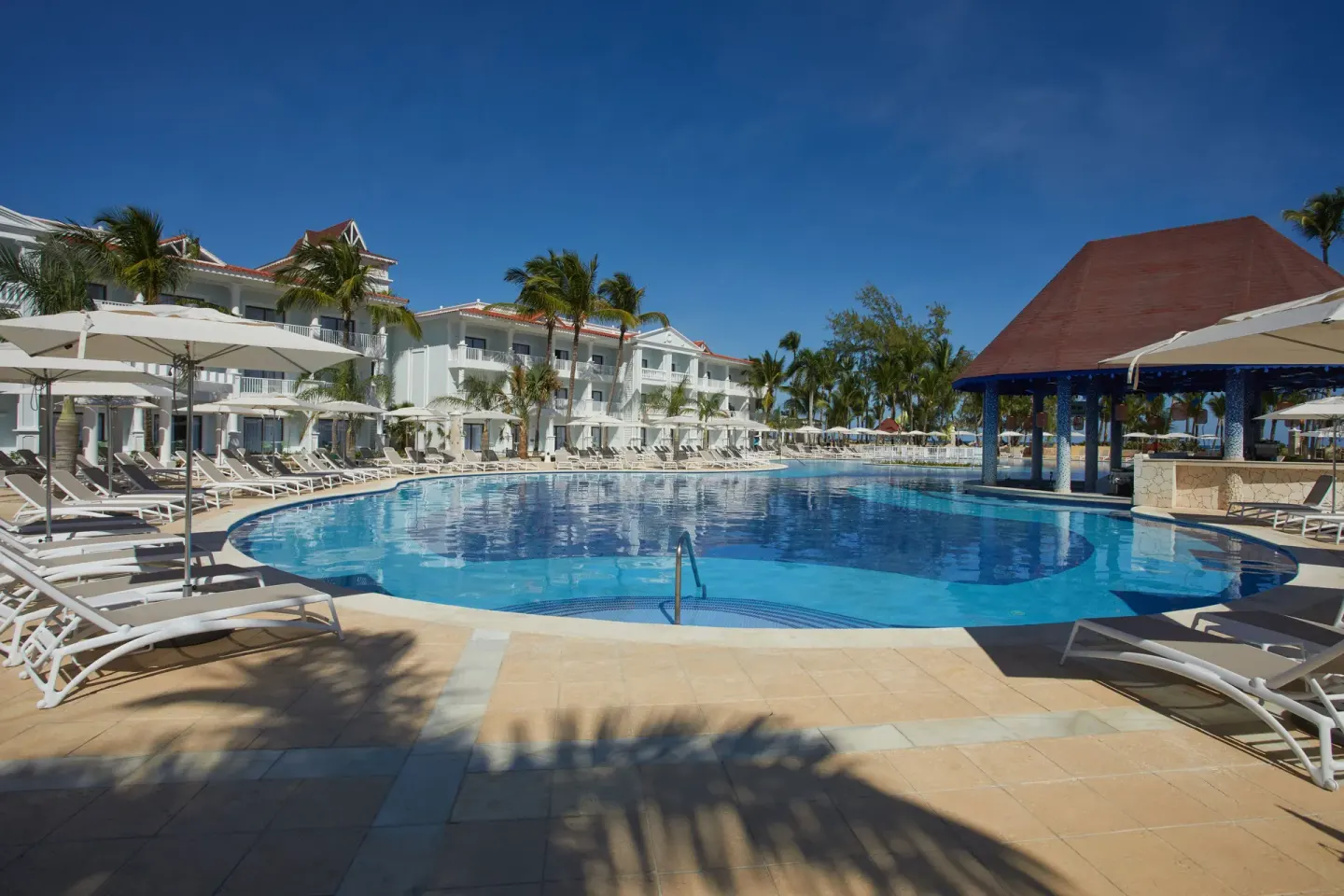 Wide pool view with umbrellas, loungers and pavilion at Bahia Principe Explore Esmeralda.