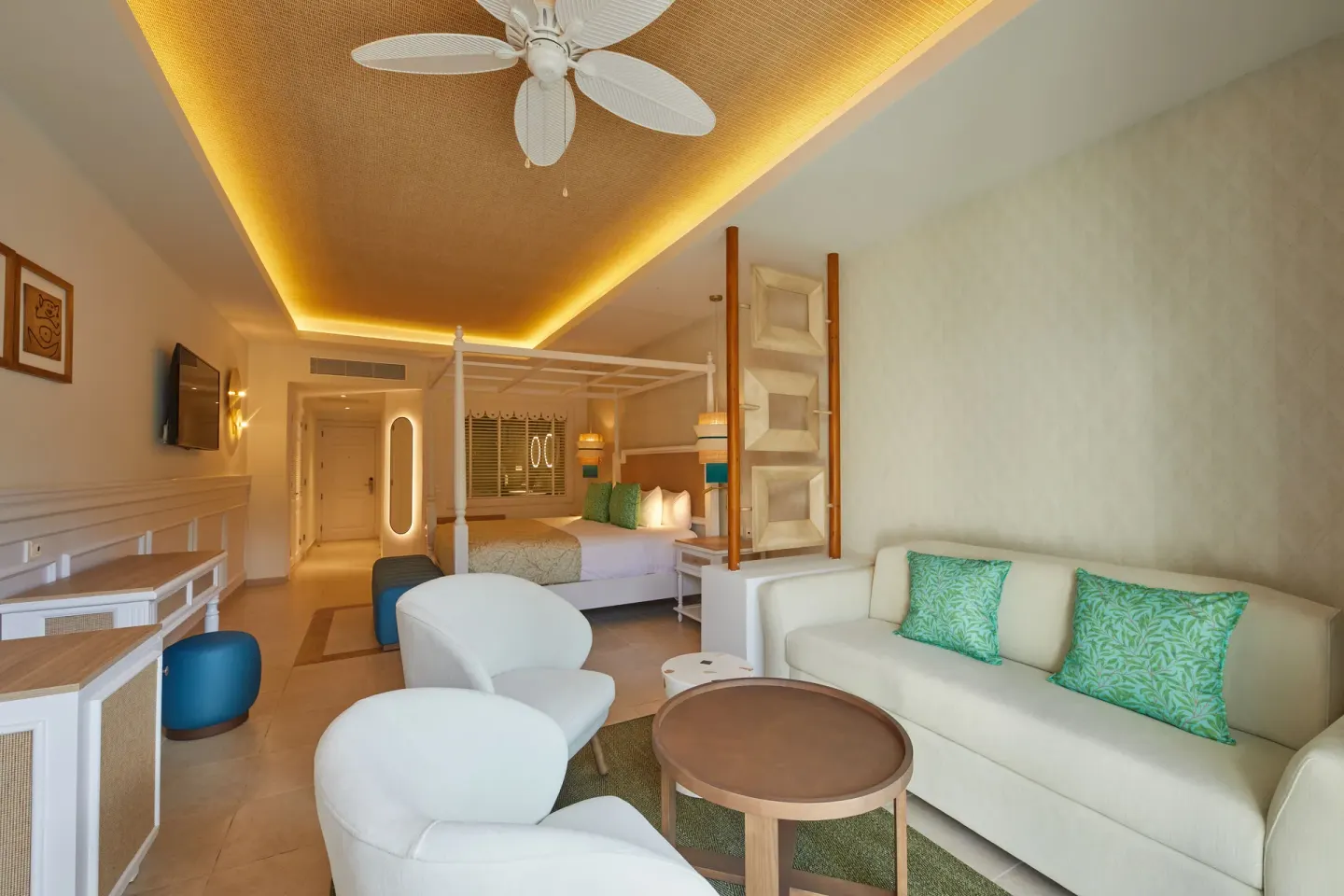 A Junior Suite at Bahia Principe Explore Esmeralda shows a bed, sofa, chairs, desk, and ceiling fan.
