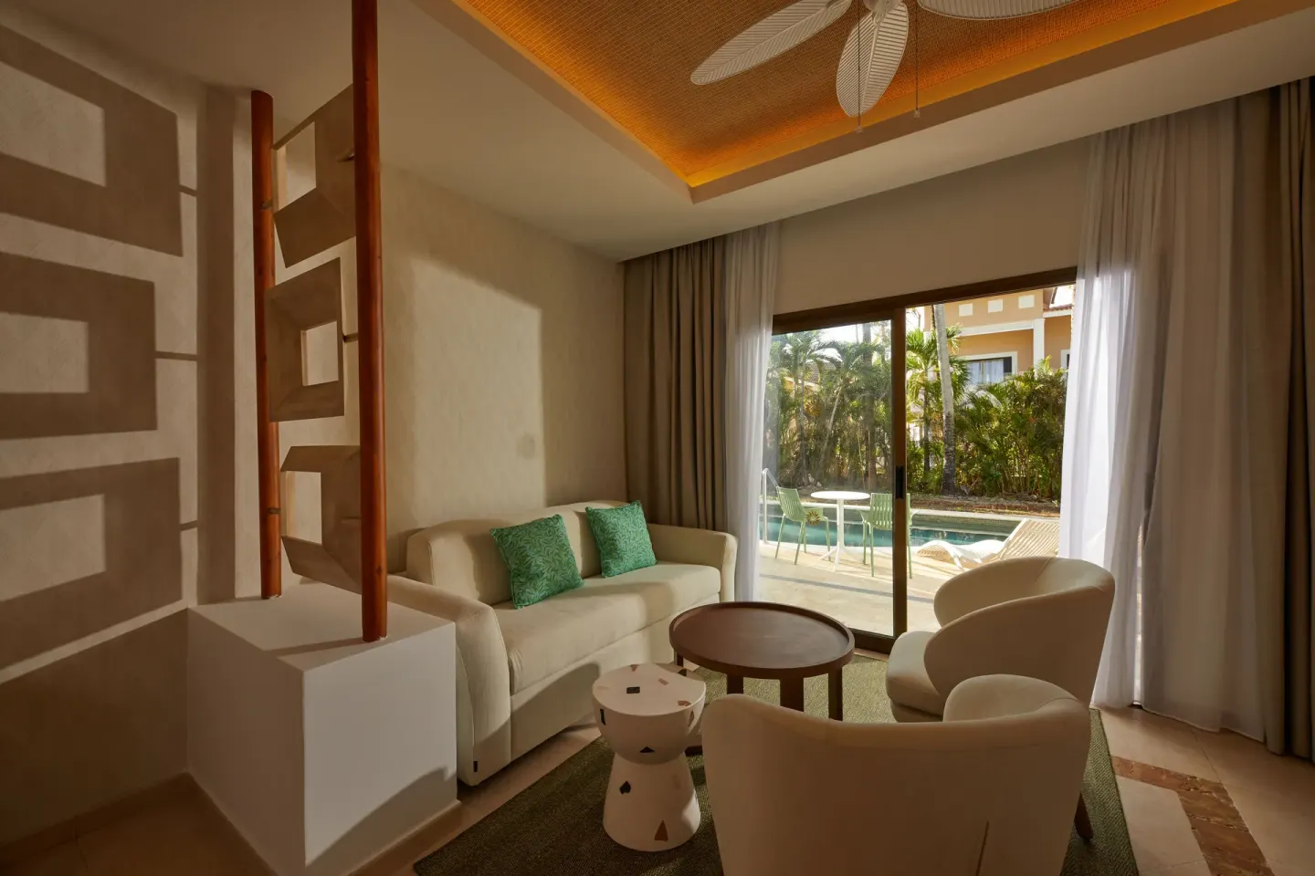 A Junior Suite at Bahia Principe Explore Esmeralda has a sofa and chairs by glass doors to the swim-up terrace.