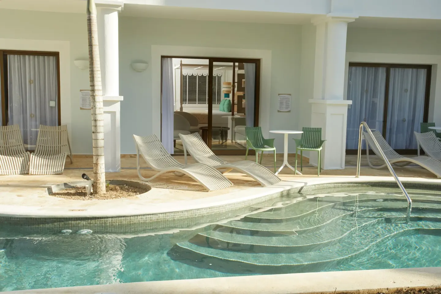 Swim-up Junior Suite patios at Bahia Principe Explore Esmeralda line a pool channel with loungers.
