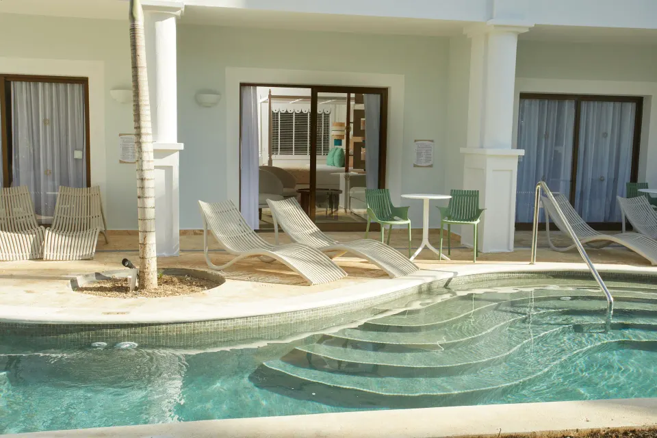 Swim-up Junior Suite patios at Bahia Principe Explore Esmeralda line a pool channel with loungers.