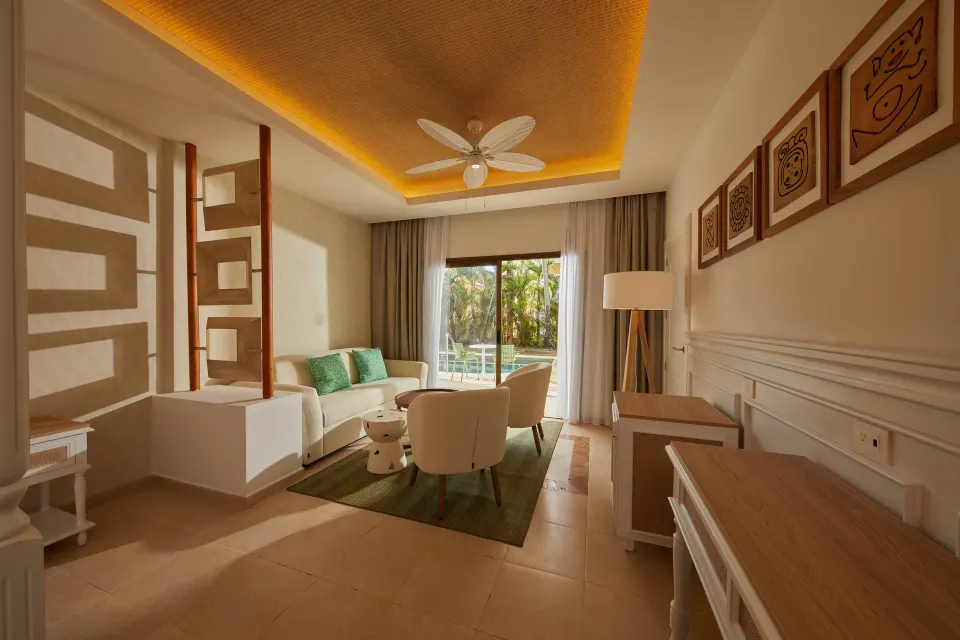The sitting area of a Junior Suite at Bahia Principe Explore Esmeralda faces sliding doors to greenery.