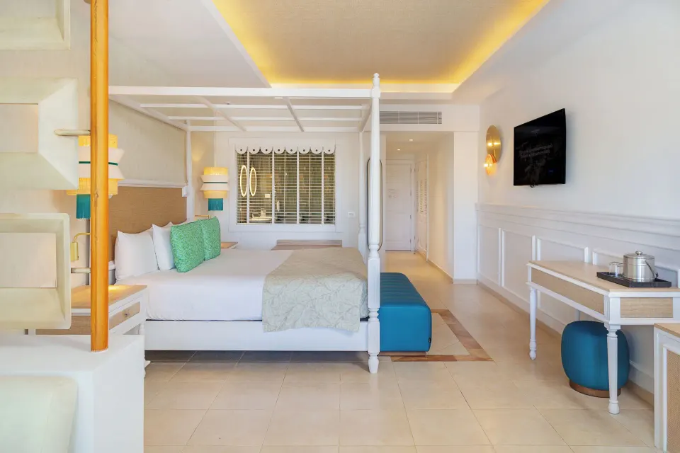Junior Suite Deluxe bed, TV, and desk area at Bahia Principe Explore Esmeralda.