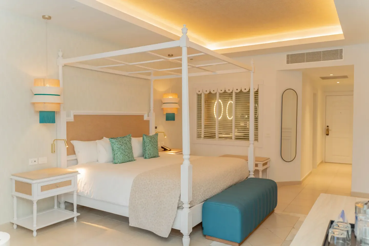 Junior Suite Deluxe king bed and teal bench at Bahia Principe Explore Esmeralda.