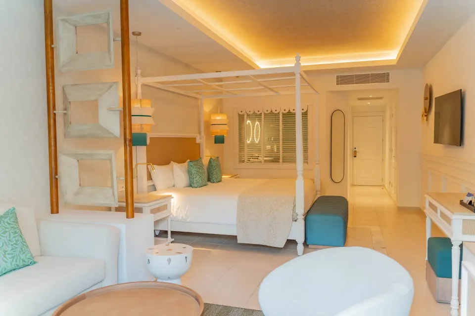 Junior Suite Deluxe king bed, TV wall, and sitting area at Bahia Principe Explore Esmeralda.