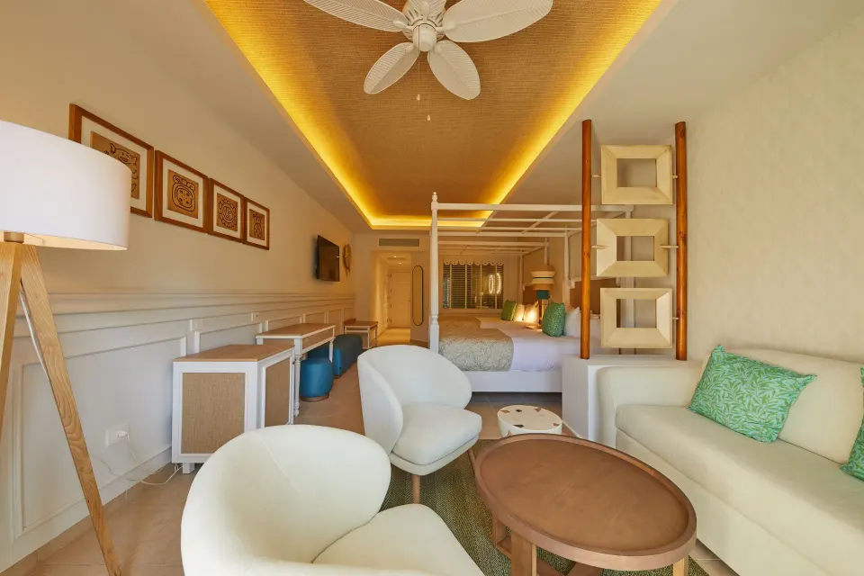 Junior Suite Deluxe sitting area with king bed beyond at Bahia Principe Explore Esmeralda.