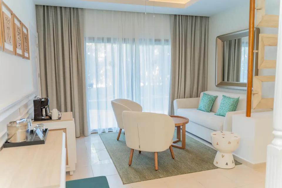 Junior Suite Deluxe lounge with sofa and balcony curtains at Bahia Principe Explore Esmeralda.