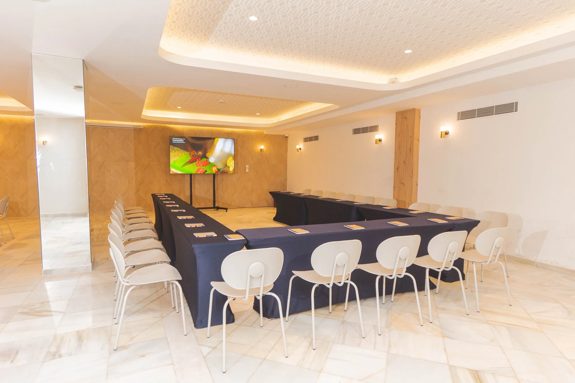 U-shaped meeting room at Bahia Principe Explore Esmeralda with white chairs and a presentation screen.