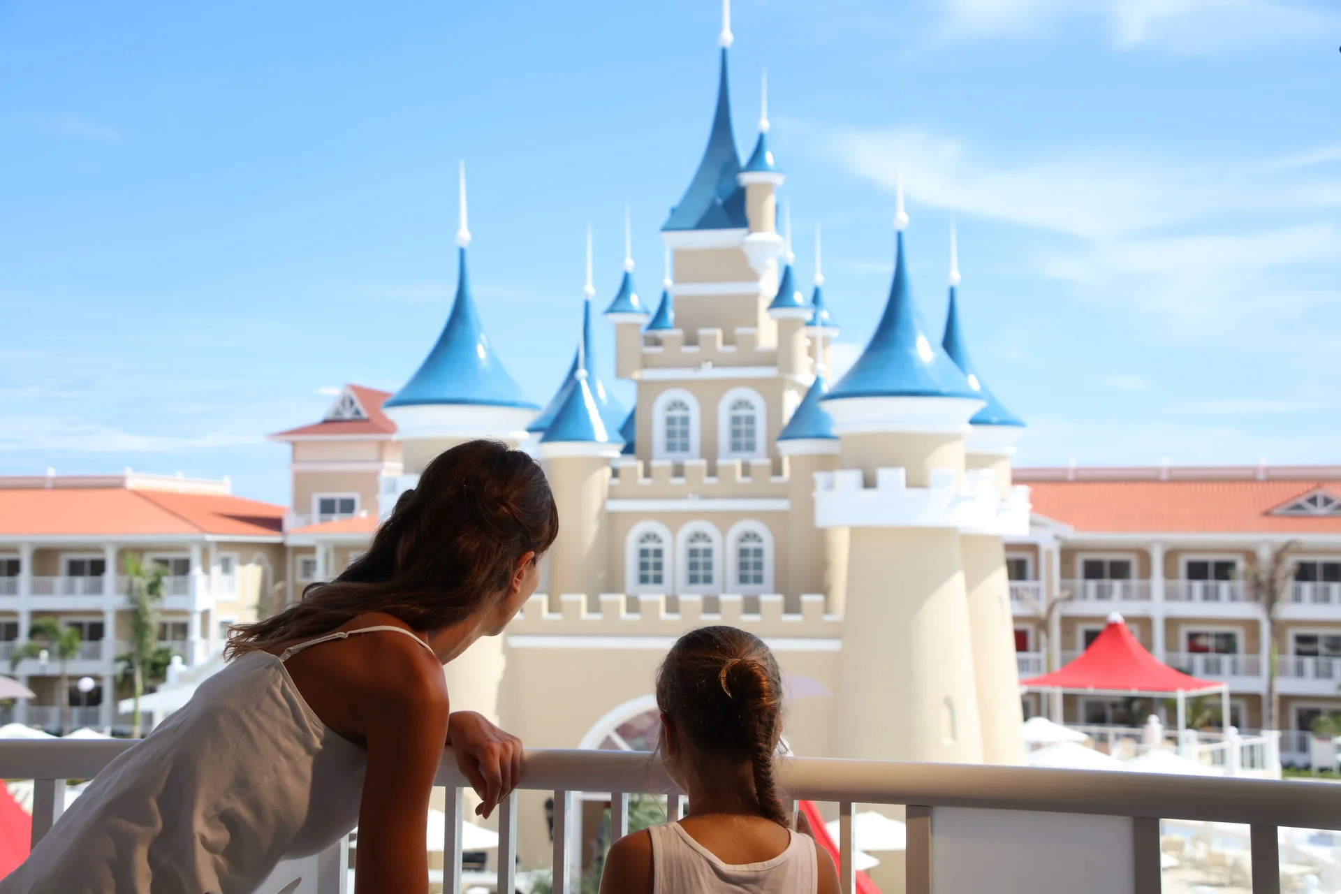 Adult and child view the castle-style facade from a balcony at Bahia Principe Explore Legend.