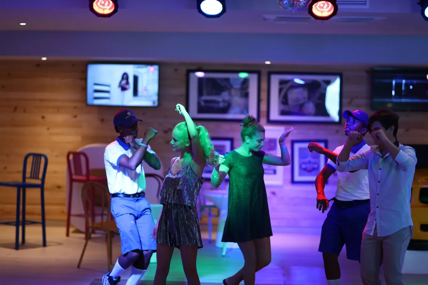 Guests dance under colored lights in an entertainment lounge at Bahia Principe Explore Legend.