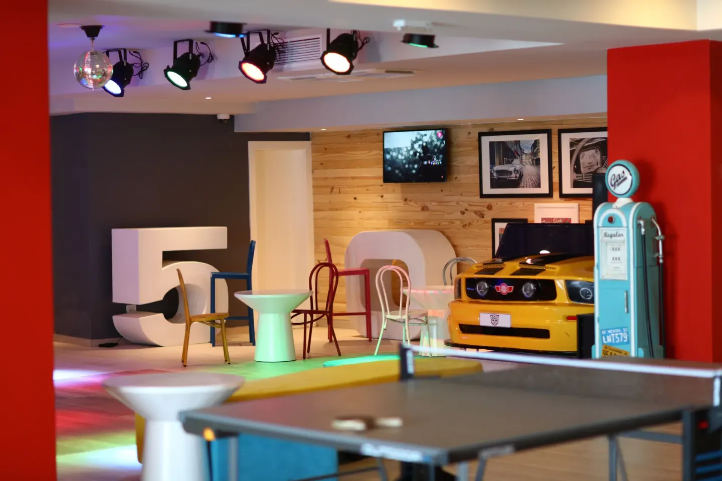 A game lounge with ping-pong, colorful chairs, and a car display at Bahia Principe Explore Legend.