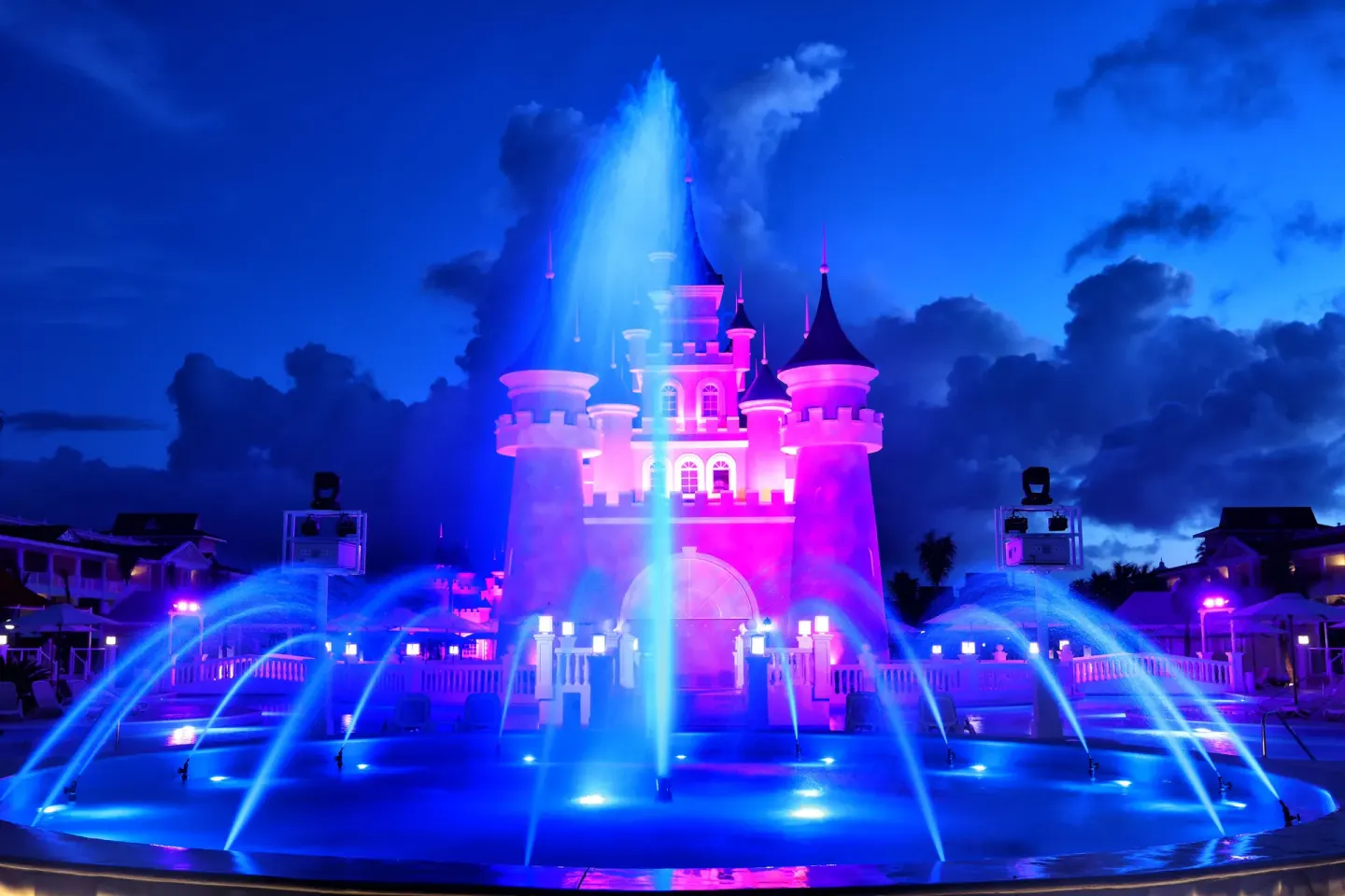 Illuminated fountain show at Bahia Principe Explore Legend in front of a castle-style backdrop at night.