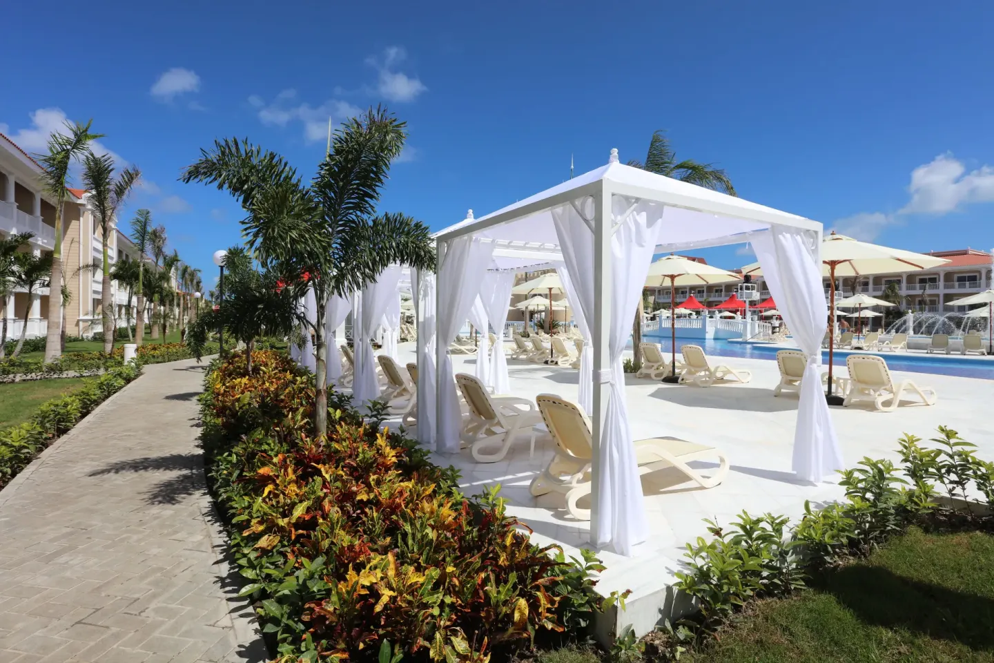 Poolside cabanas at Bahia Principe Explore Legend with loungers beside the swimming pool.