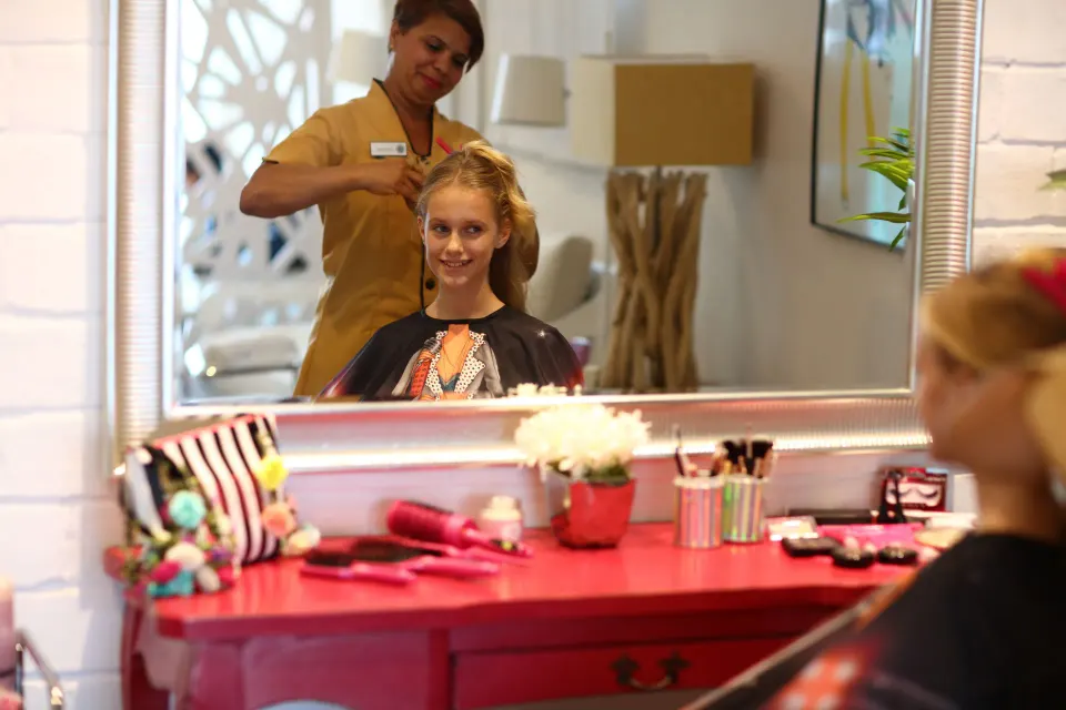 A child receives a hairstyle at a salon vanity at Bahia Principe Explore Legend.