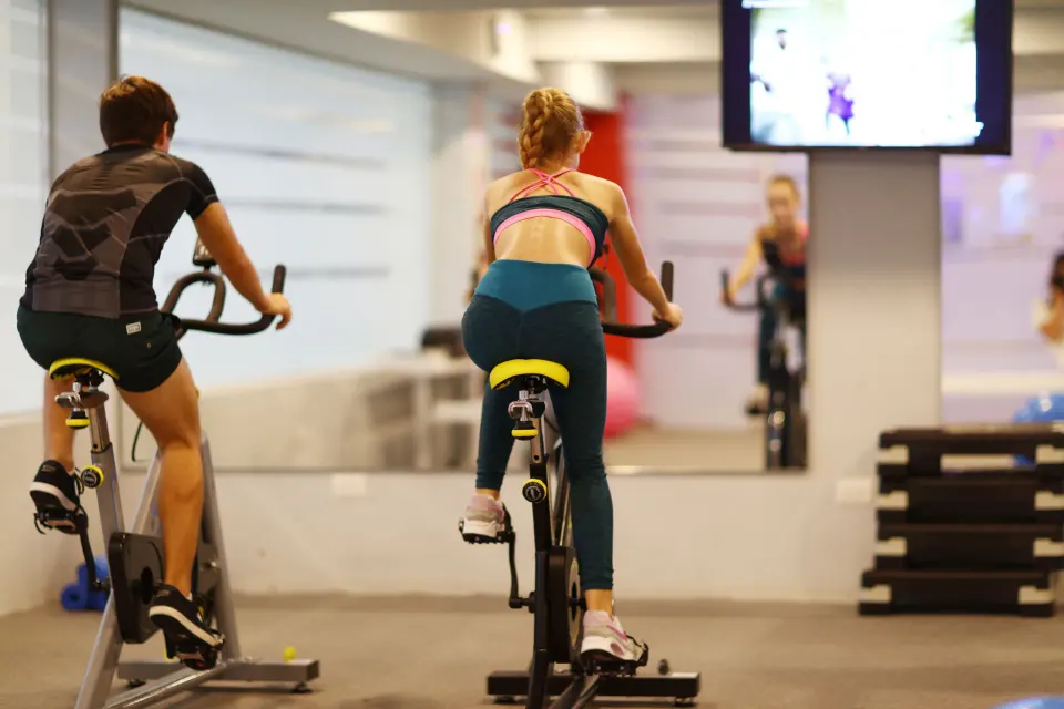 Two guests ride stationary bikes in the gym at Bahia Principe Explore Legend.