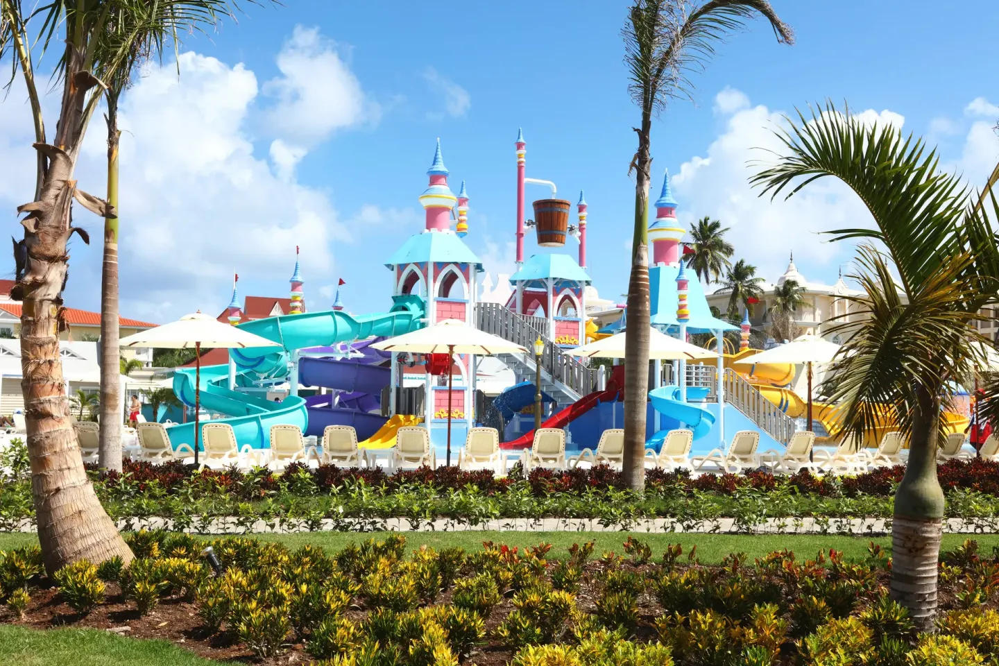 A colorful water park with slides and palm trees at Bahia Principe Explore Legend.