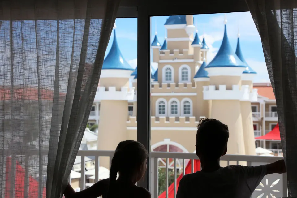 Junior Suite Deluxe Castle View window at Bahia Principe Explore Legend with guests looking toward the castle facade.
