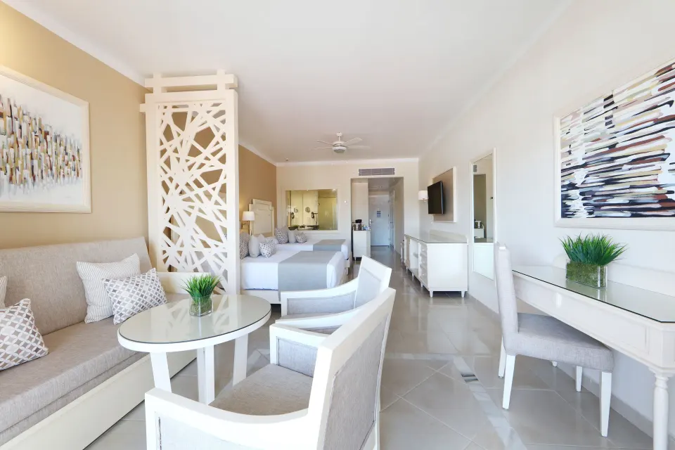 Junior Suite Deluxe lounge, desk, and sleeping area at Bahia Principe Explore Legend.