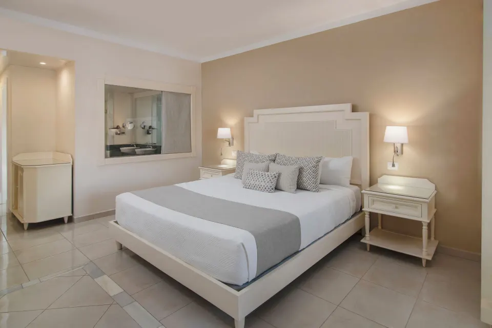 Junior Suite king bed with bedside lamps at Bahia Principe Explore Legend.