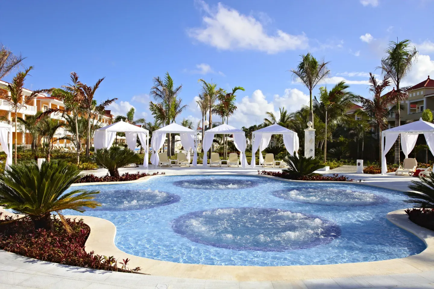 Small bubbling pool with cabanas and palm landscaping at Bahia Principe Grand Aquamarine.