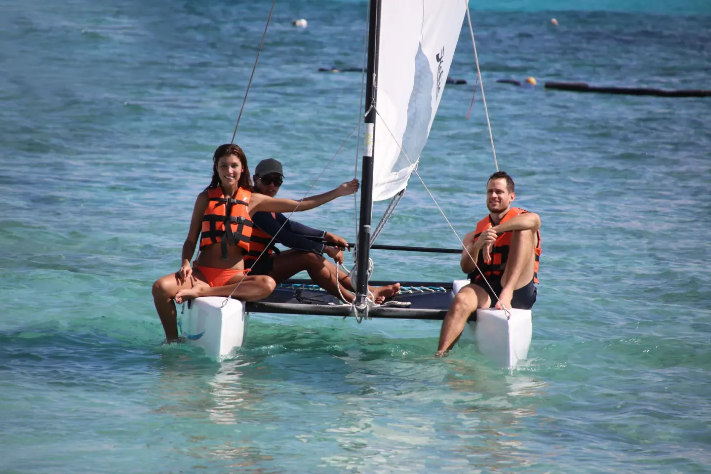 Guests sailing a small catamaran on turquoise water at Bahia Principe Grand Aquamarine.