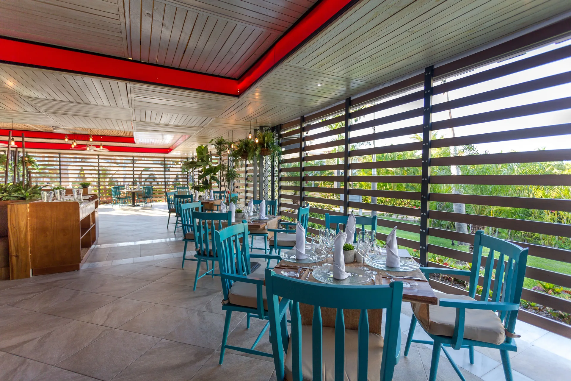 Open-air dining room with turquoise chairs at Bahia Principe Grand Aquamarine.