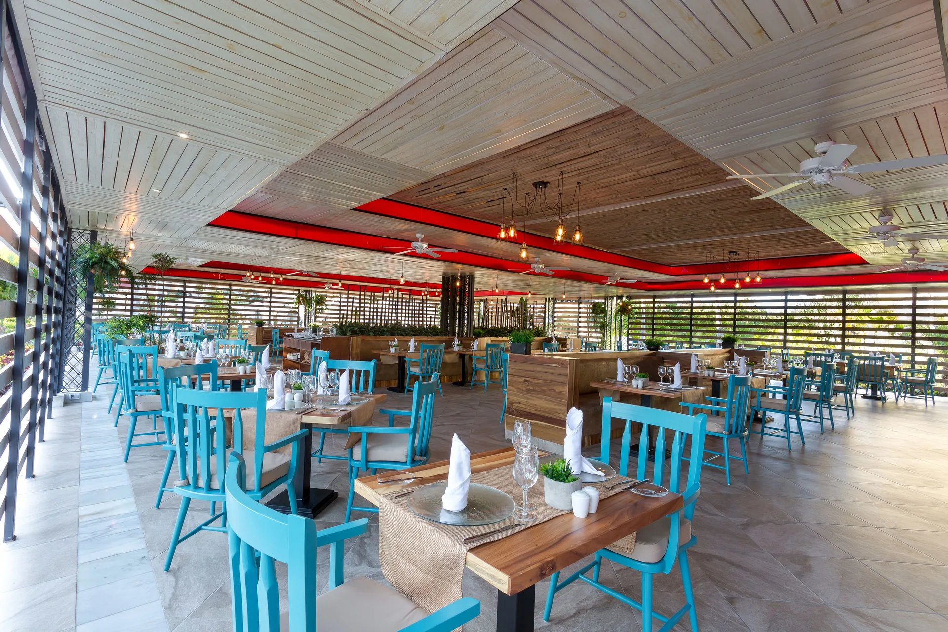 Open-air restaurant with turquoise chairs at Bahia Principe Grand Aquamarine.