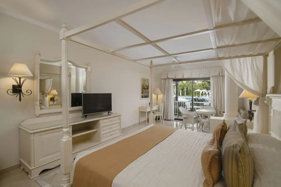 Junior Suite superior room with canopy bed and balcony at Bahia Principe Grand Aquamarine.