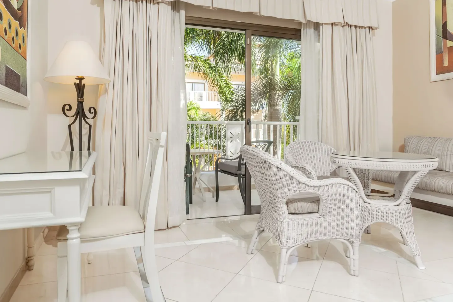 Junior Suite wicker seating area by balcony doors at Bahia Principe Grand Aquamarine.