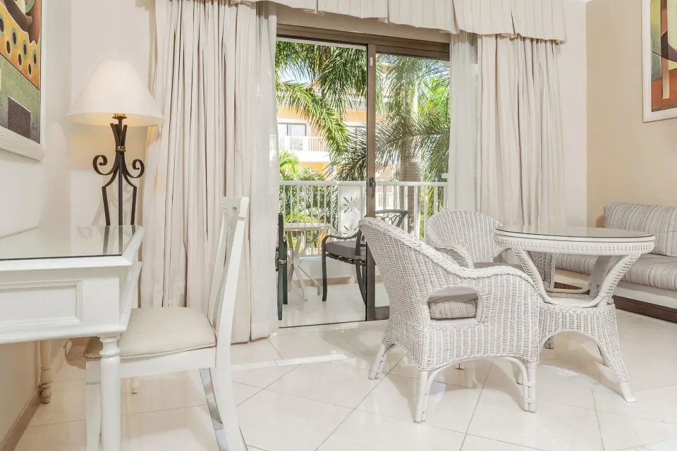 Junior Suite wicker seating area by balcony doors at Bahia Principe Grand Aquamarine.