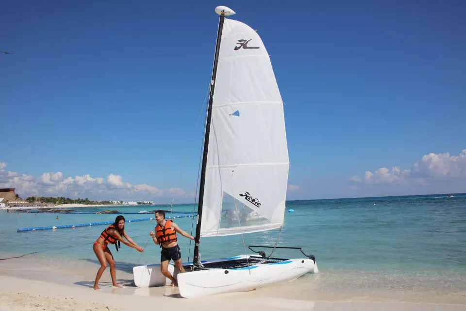 Small sailboat on the shoreline with guests preparing to launch at Bahia Principe Grand Coba